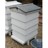 A traditional wooden bee hive, painted white,  with zinc roof