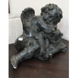 A verdigris-patinated pottery recumbent putto in the Regency style