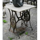 A vintage cast iron Singer sewing machine treadle base with stone slab table top