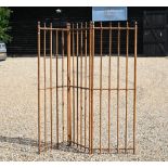 An antique French three fold room divider of pitched pine rods with brass fittings, each panel 60 cm