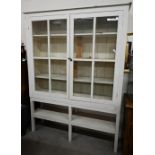 A large cream painted pine bookcase with glazed doors enclosing three shelves with open shelf below,