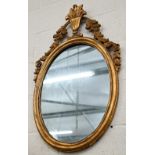 An old oval giltwood framed mirror with urn pediment