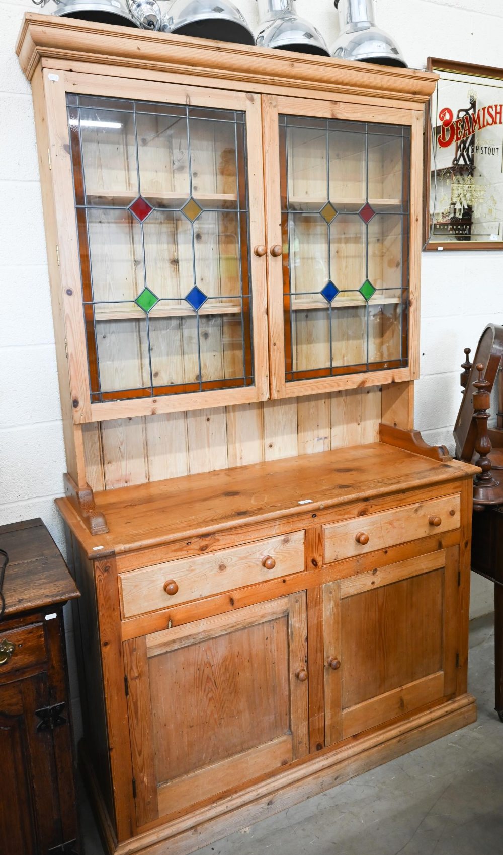 A vintage waxed pine dresser, the raised back with leaded and stained glass doors on base with two