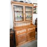 A vintage waxed pine dresser, the raised back with leaded and stained glass doors on base with two