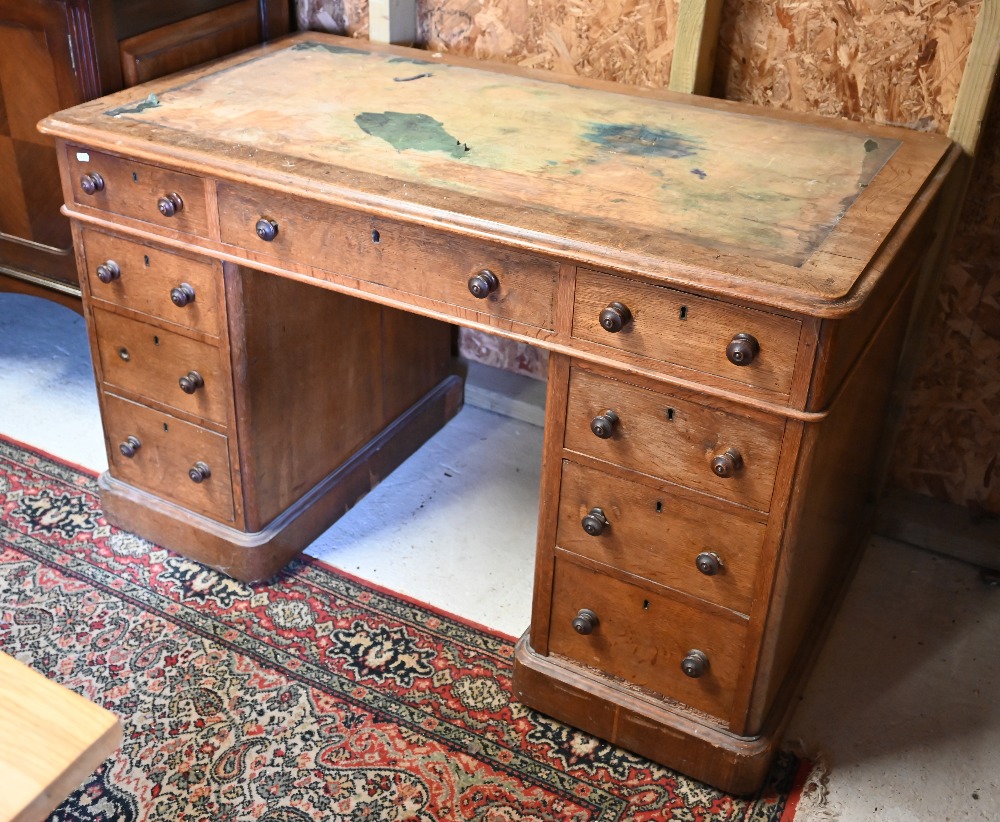 A Victorian oak twin pedestal desk, with nine drawers, raised on plinths and concealed castors -