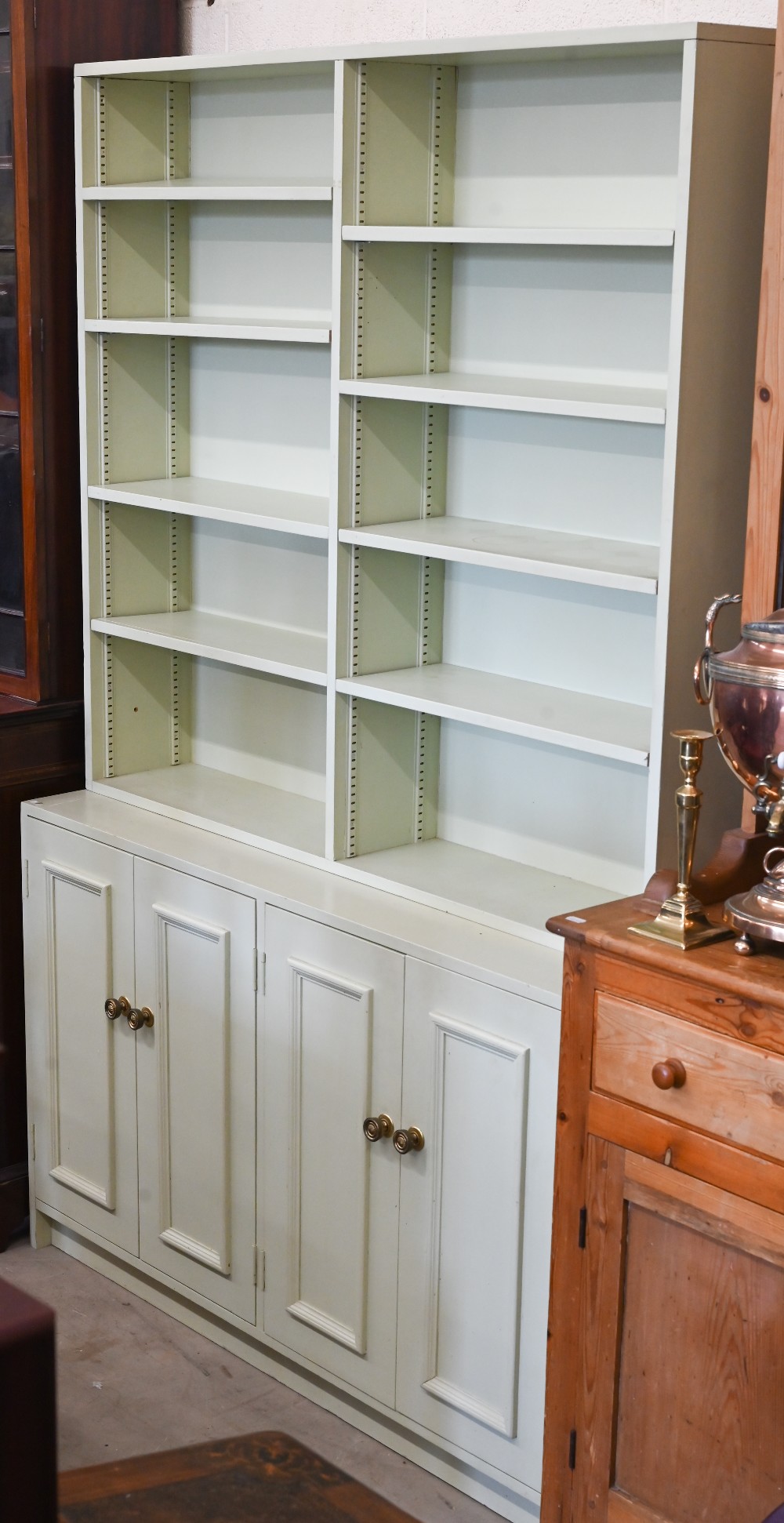 A green-painted bookcase with adjustable open shelving over panelled cupboards, 122 cm wide x 40