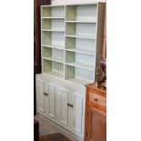 A green-painted bookcase with adjustable open shelving over panelled cupboards, 122 cm wide x 40