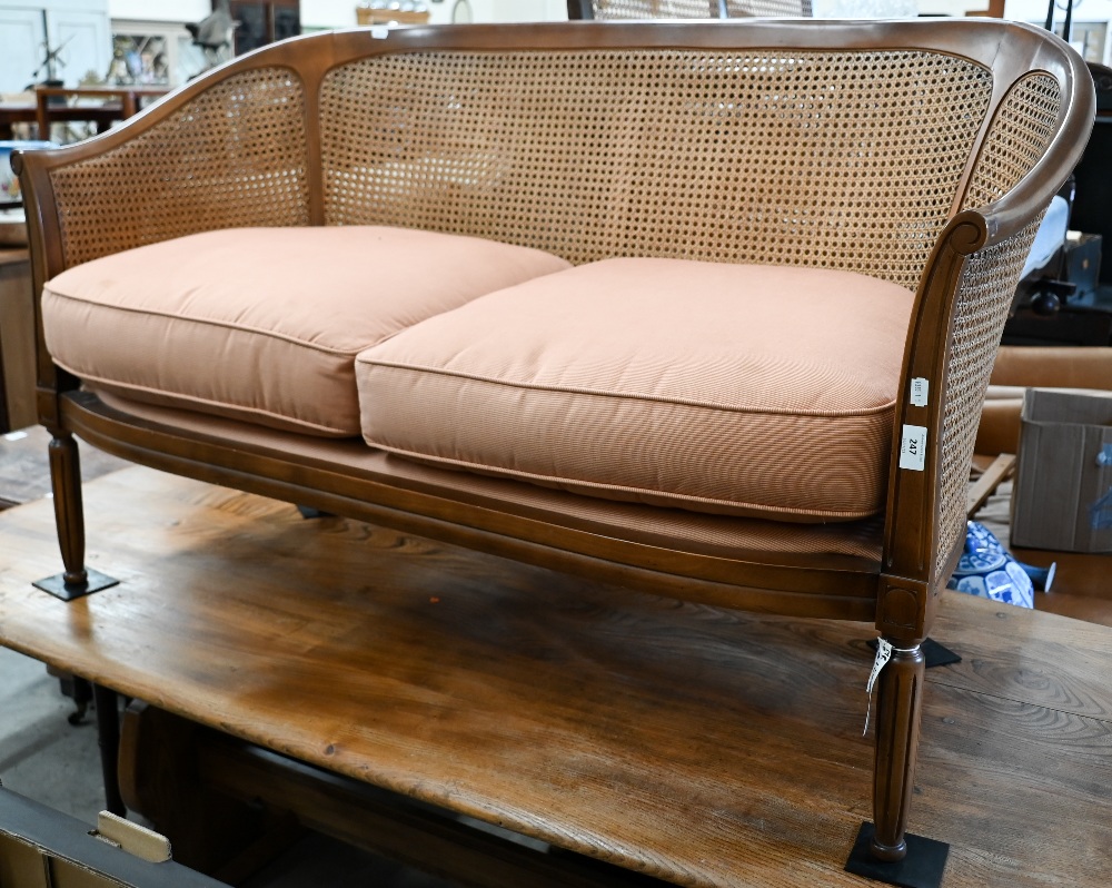 A walnut framed double caned two seater bergere sofa on fluted supports, 130 cm wide x 60 cm deep