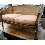 A walnut framed double caned two seater bergere sofa on fluted supports, 130 cm wide x 60 cm deep