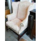 A mahogany framed wingback armchair in peach damask fabric