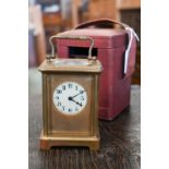 A brass carriage clock, 14.5 cm high, in red leather case