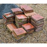 A quantity of old terracotta square tiles, 23 x 23 cm and nineteen crenalated edging tiles