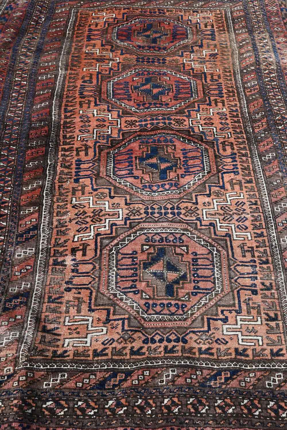 A Persian Balouch rug with four octagonal medallions on brick ground with brown repeating border, - Image 3 of 4