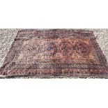 A Persian Balouch rug with four octagonal medallions on brick ground with brown repeating border,