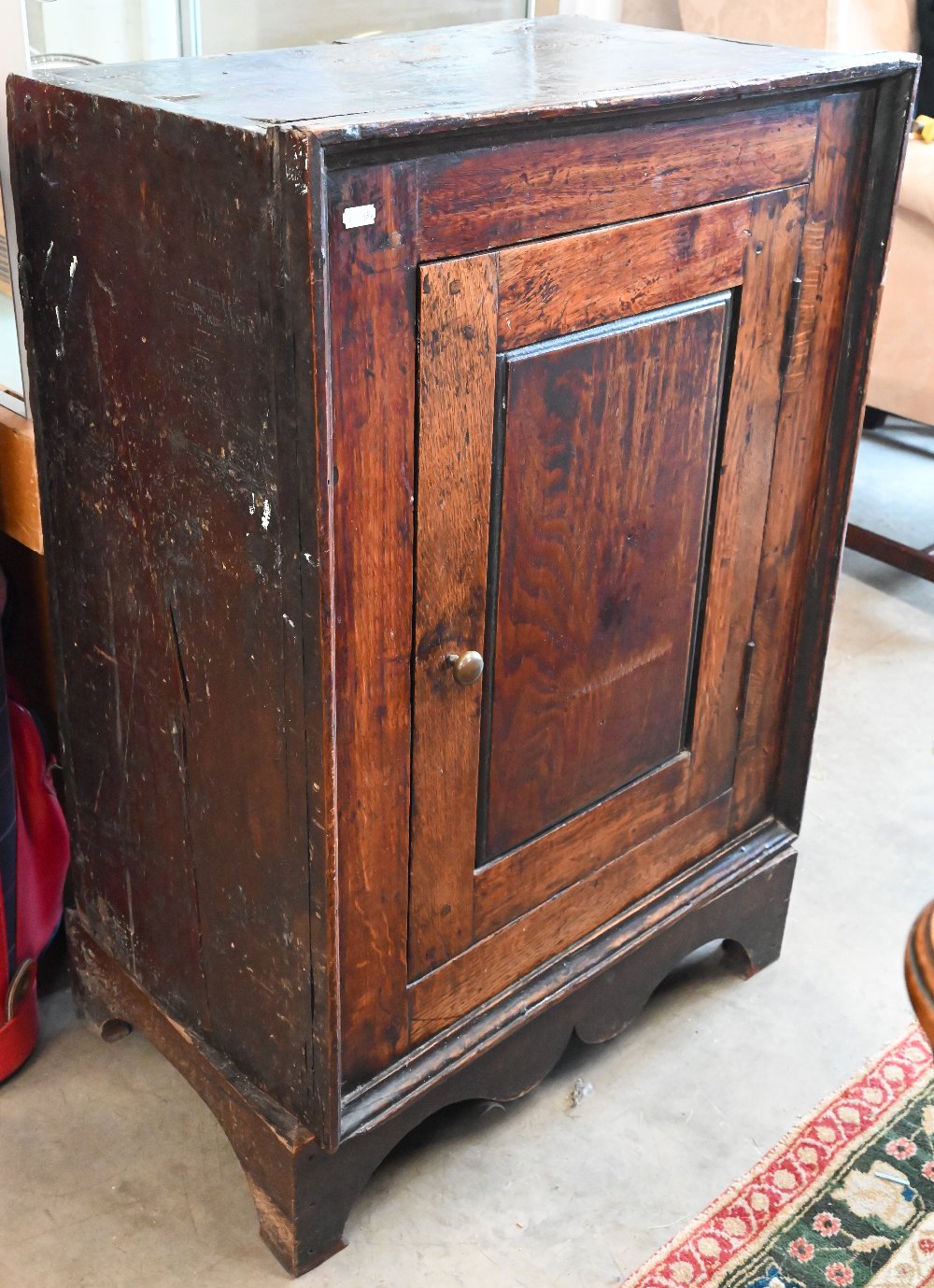 An antique Provincial oak side cabinet on stand with single panelled door enclosing shelves, 60 x 35