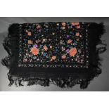 A Chinese silk fringed piano shawl, the black ground richly decorated with flowers and foliage,