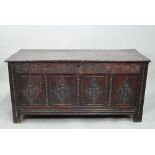 A late 17th century carved oak coffer, the two plank top over a lunette carved frieze and four
