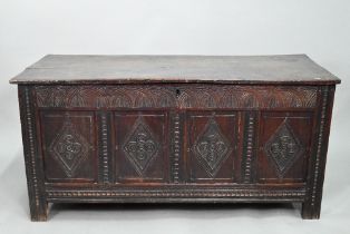 A late 17th century carved oak coffer, the two plank top over a lunette carved frieze and four