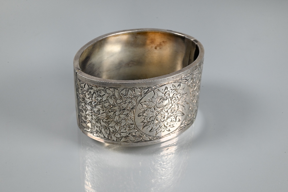 A wide white metal oval half-hinged bangle with engraved floral decoration to front, stamped ' - Image 2 of 5