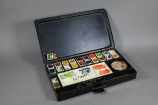 An Edwardian artist's black japanned watercolour box, the hinged lid with gilded coat of arms and