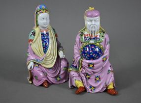A pair of Dresden figures of a Chinese couple in pink official's robes painted with flowers and