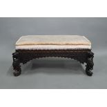 A carved Burmese hardwood stool, with drop-in fabric seat cushion, raised on carved animalistic