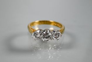 A three-stone diamond ring, the graduated diamonds claw set in platinum, with 18ct yellow gold