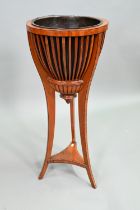 An antique satinwood jardinière stand with brass liner and slatted sides, raised on slender tripod