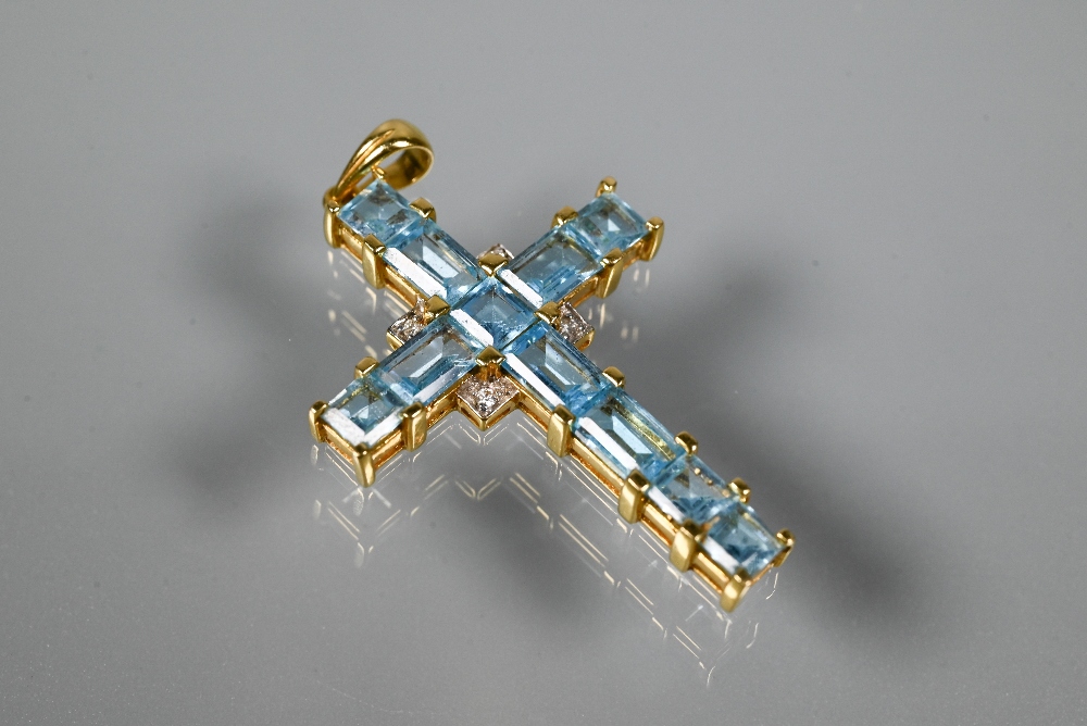 A cross-shaped pendant set overall with square and rectangular cut blue topaz, diamond set centre,