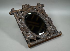 A late 19th century Black Forest wall mirror, the oval bevelled edge mirror set within a frame