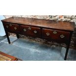 An 18th century oak low dresser, the wide single plank top over three drawers within a shaped apron,