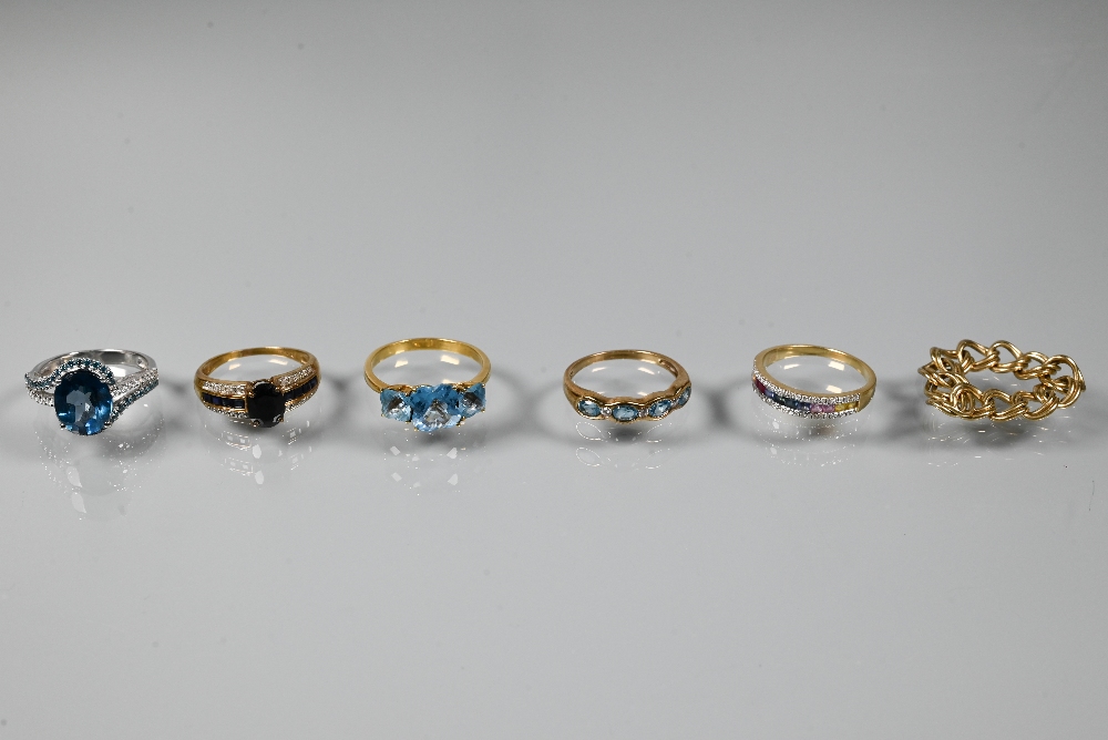 Five various rings, three set blue topaz, one channel set with coloured sapphires, one dark blue