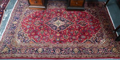 An old Persian Kashan rug, the red ground centred by a floral medallion, 215 cm x 135 cm