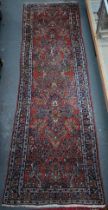 An old Persian Sarouk runner, the stylised floral vine design on pale red ground, 358 cm x 107 cm