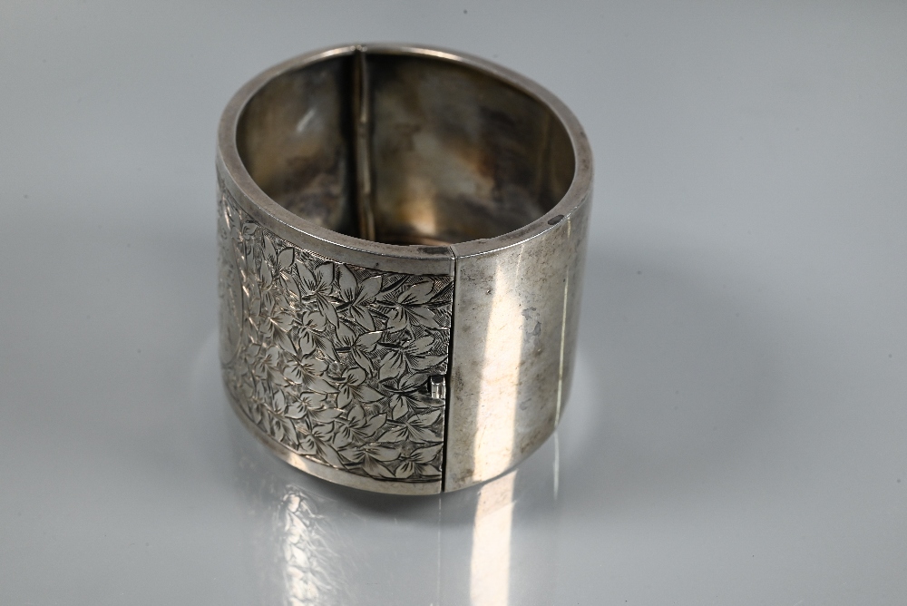 A wide white metal oval half-hinged bangle with engraved floral decoration to front, stamped ' - Image 3 of 5