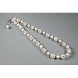 A cultured pearl necklace comprising uniform round cultured pearls alternating with smaller pearl