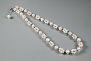 A cultured pearl necklace comprising uniform round cultured pearls alternating with smaller pearl