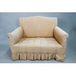 A small country house upholstered two seater sofa, with hump back, raised on walnut legs to