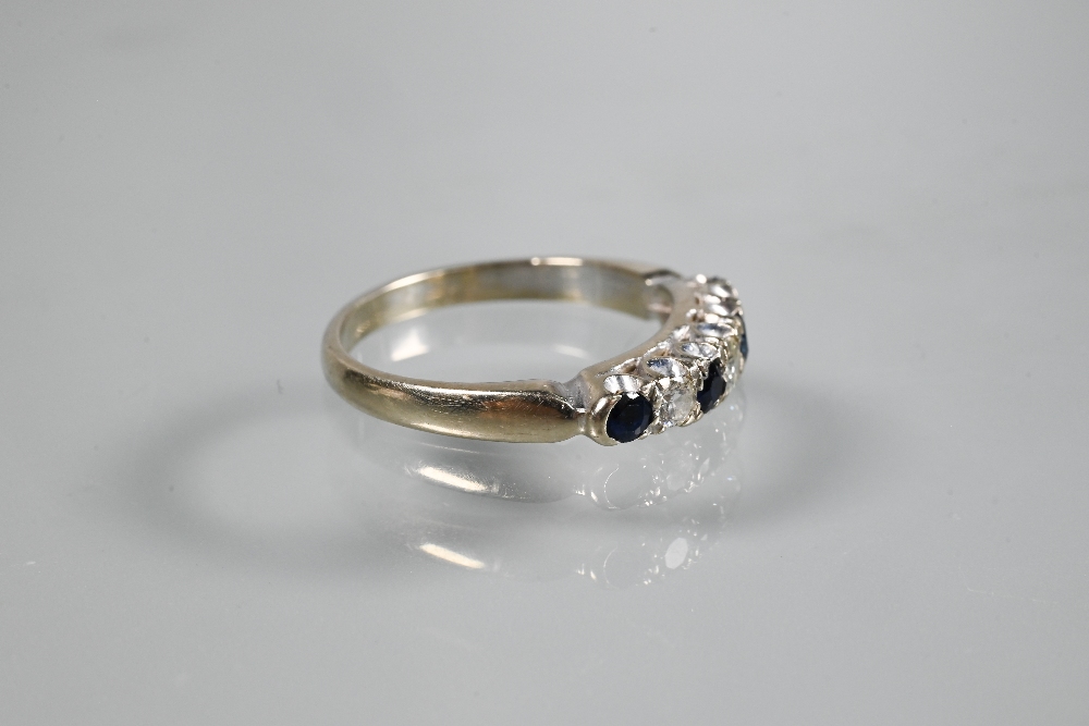 A seven stone ring, the alternate circular dark blue sapphires and diamonds in white metal setting