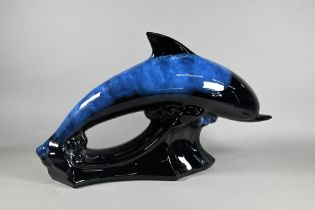 A large pottery model of a leaping dolphin, on naturalistic wave base, 23 x 41 cm