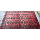 An old North East Persian Turkoman rug, the red ground with three rows of stylised guls, 252 cm x