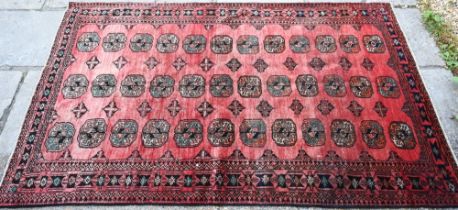 An old North East Persian Turkoman rug, the red ground with three rows of stylised guls, 252 cm x