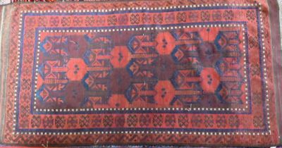 An antique Belouch rug, the red-brown ground with narrow blue bands and wide kelim ends, 202 cm x