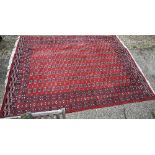 A contemporary Turkoman red ground carpet, the repeating gul design within wide borders, 364 cm x