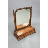 A George III cross-banded walnut toilet mirror, raised on a three drawer base on ogee moulded