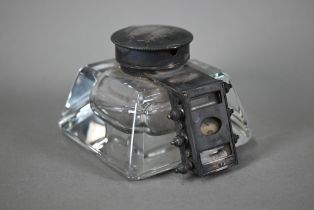 An unusual Edwardian glass inkwell, mounted with a hinged silver cover and perpetual calendar (lacks