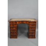 A continental walnut leather topped desk, of inverted serpentine form with an arrangement of