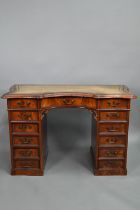 A continental walnut leather topped desk, of inverted serpentine form with an arrangement of