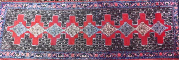 A contemporary North West Persian Senneh runner, the lozenge pole design on red ground, 300 cm x 100