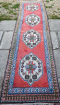 A Turkish Kazak design runner, the four diamond pole design on red ground, 323 cm x 78 cm